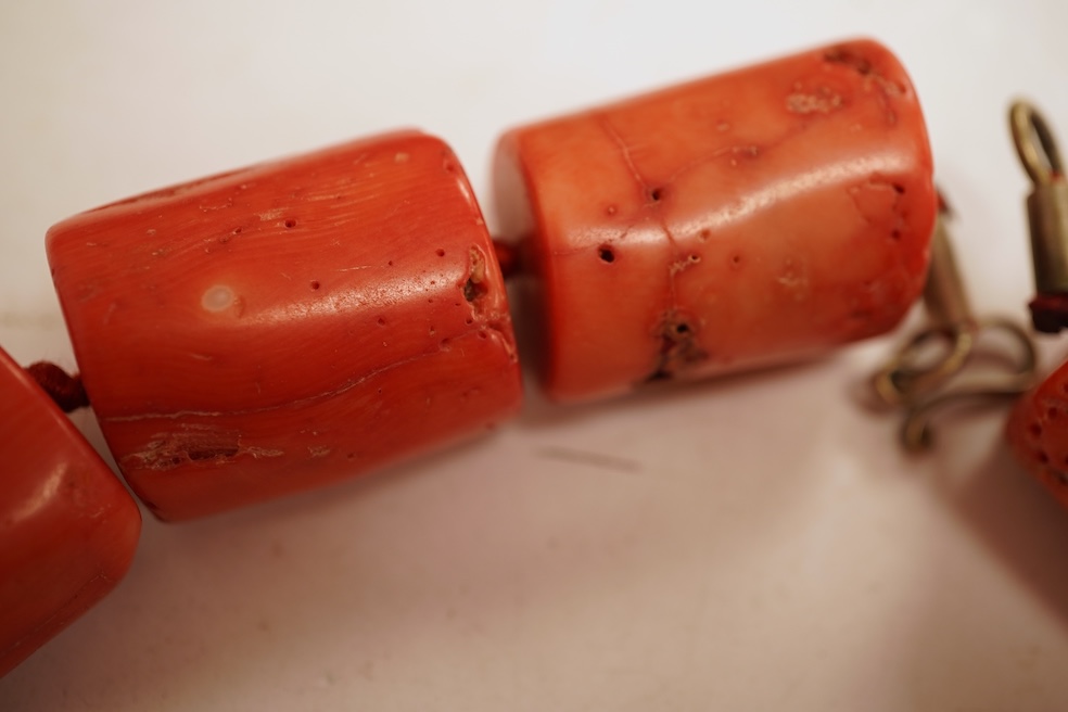 Two coral bead necklaces, one composed of large cylindrical coral beads, approximately 2.5-3.5cm each, total length 49cm; and a bracelet composed of carved coral beads spaced by smaller pink coral beads, on an elasticate
